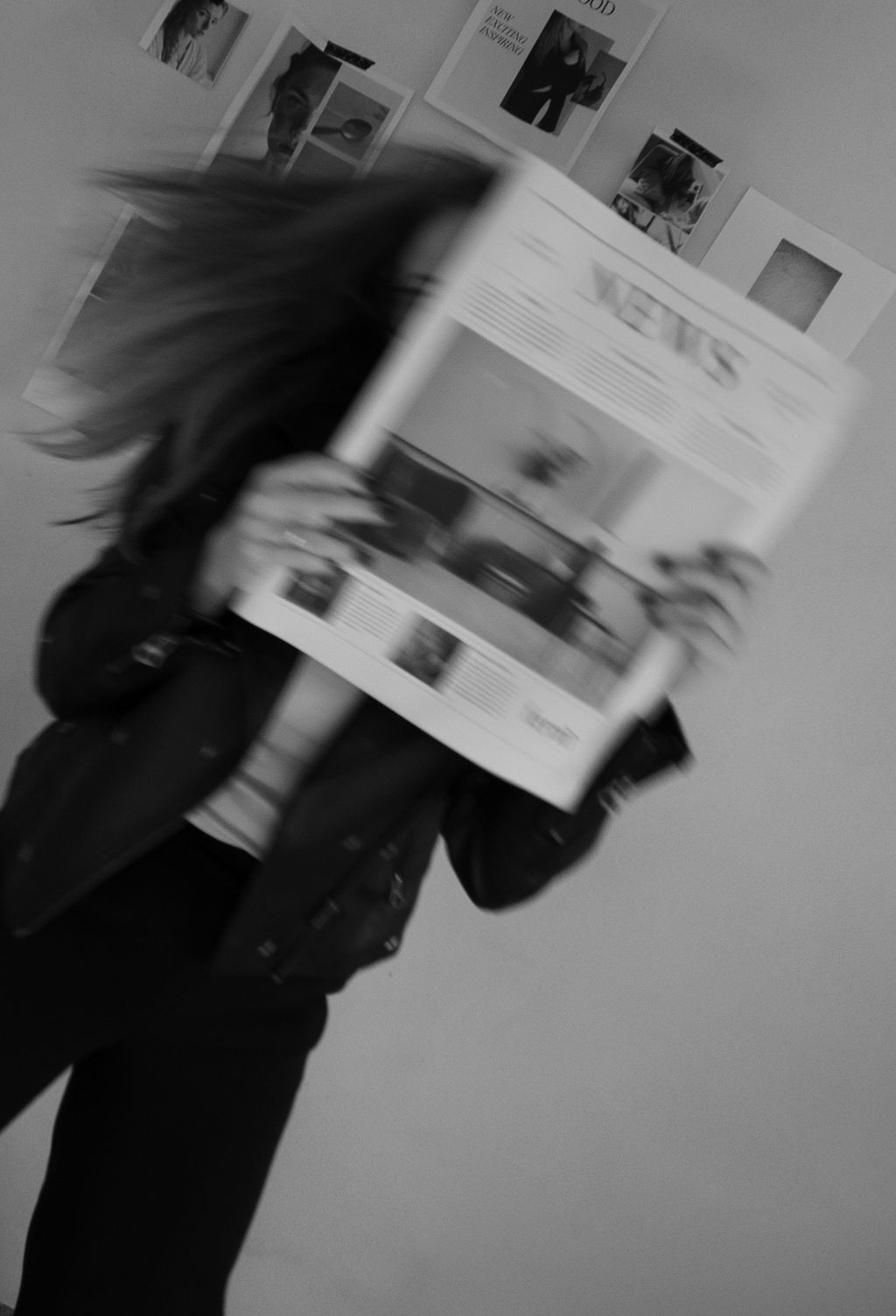 Motion blurred black and white photo of someone flipping through a magazine in front of a photo wall