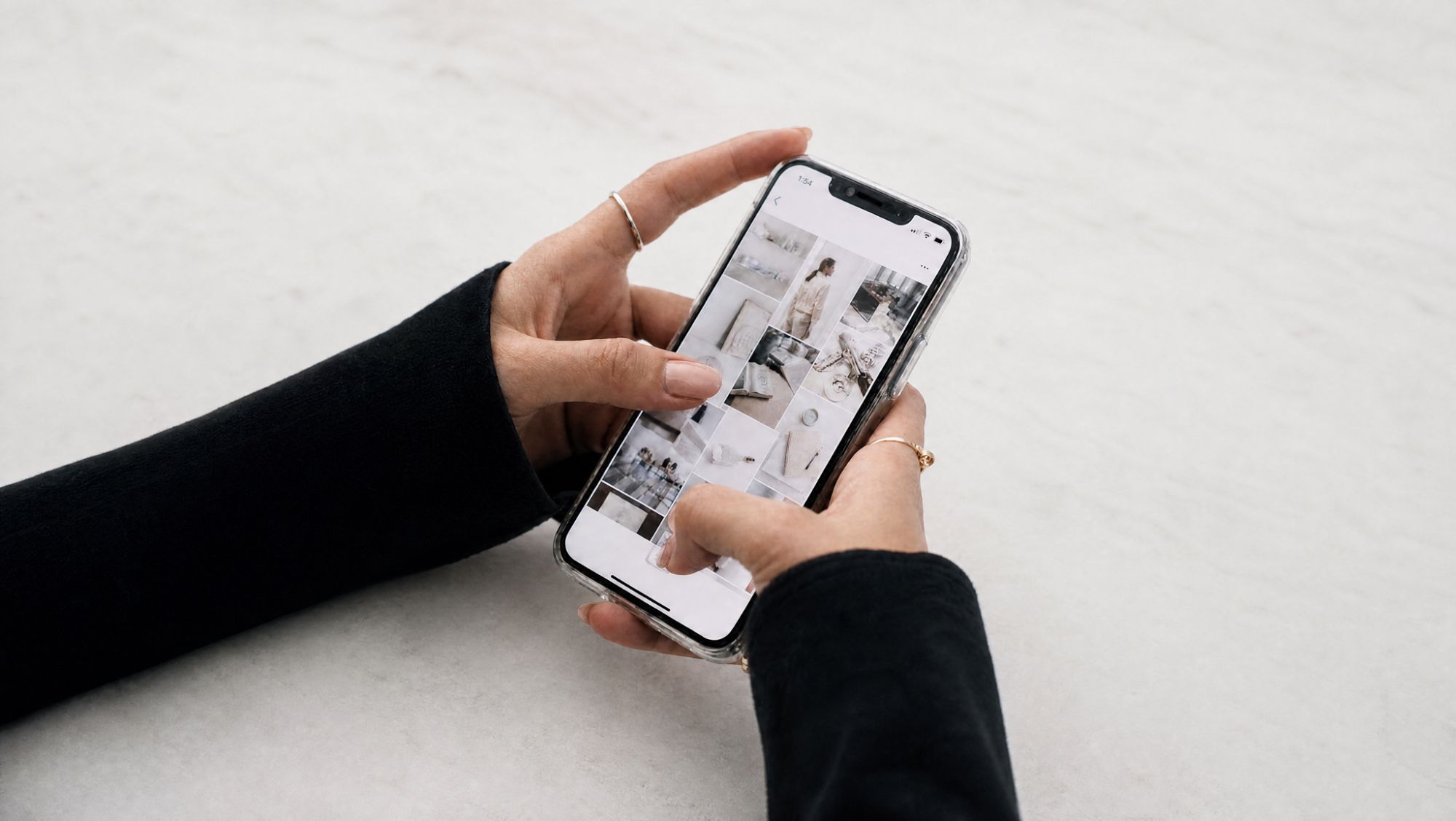 Close-up of two hands scrolling through a grid of photos on a smartphone